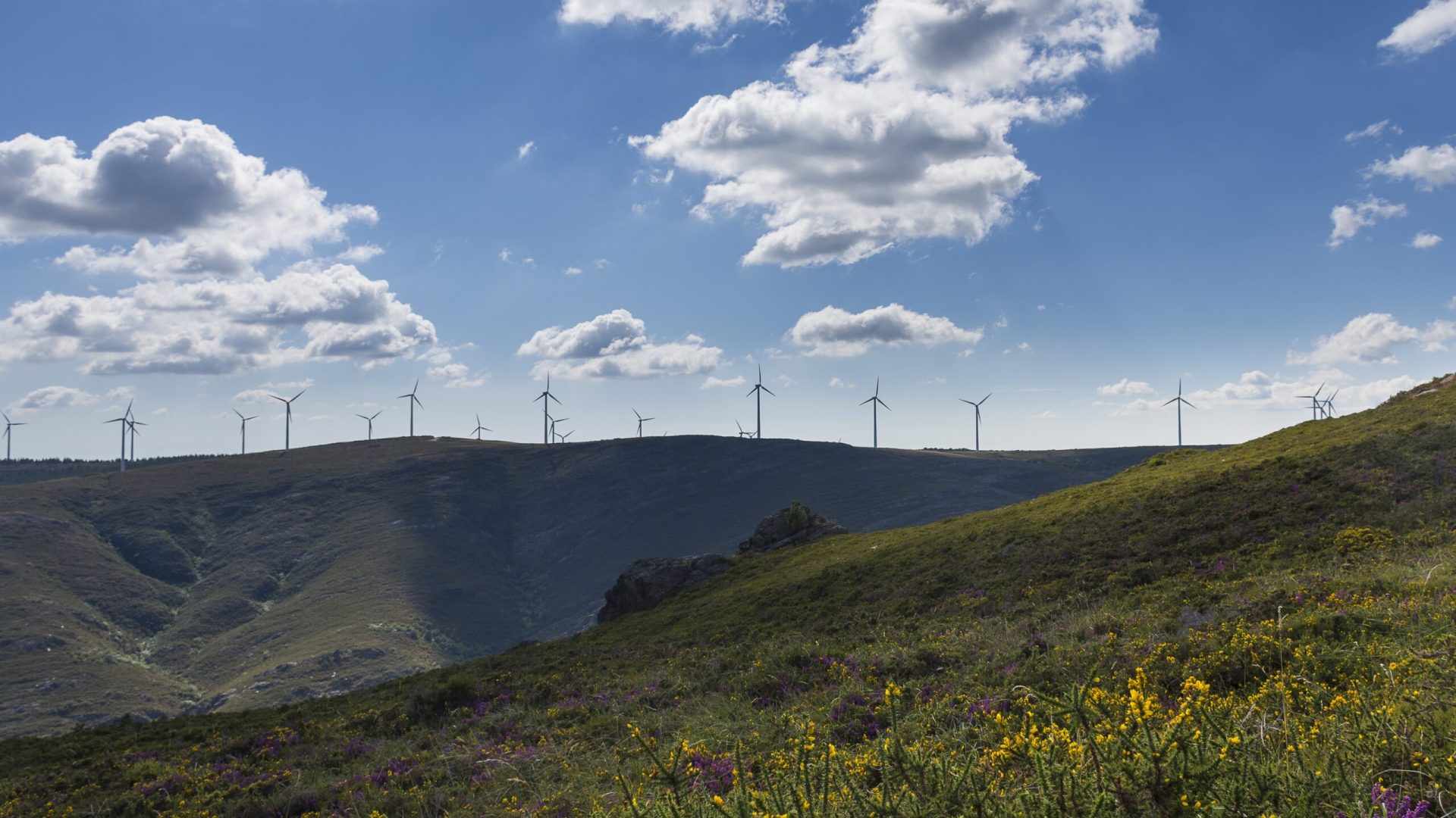 A beautiful view of windmills on a hill with a cloudy blue sky in the background